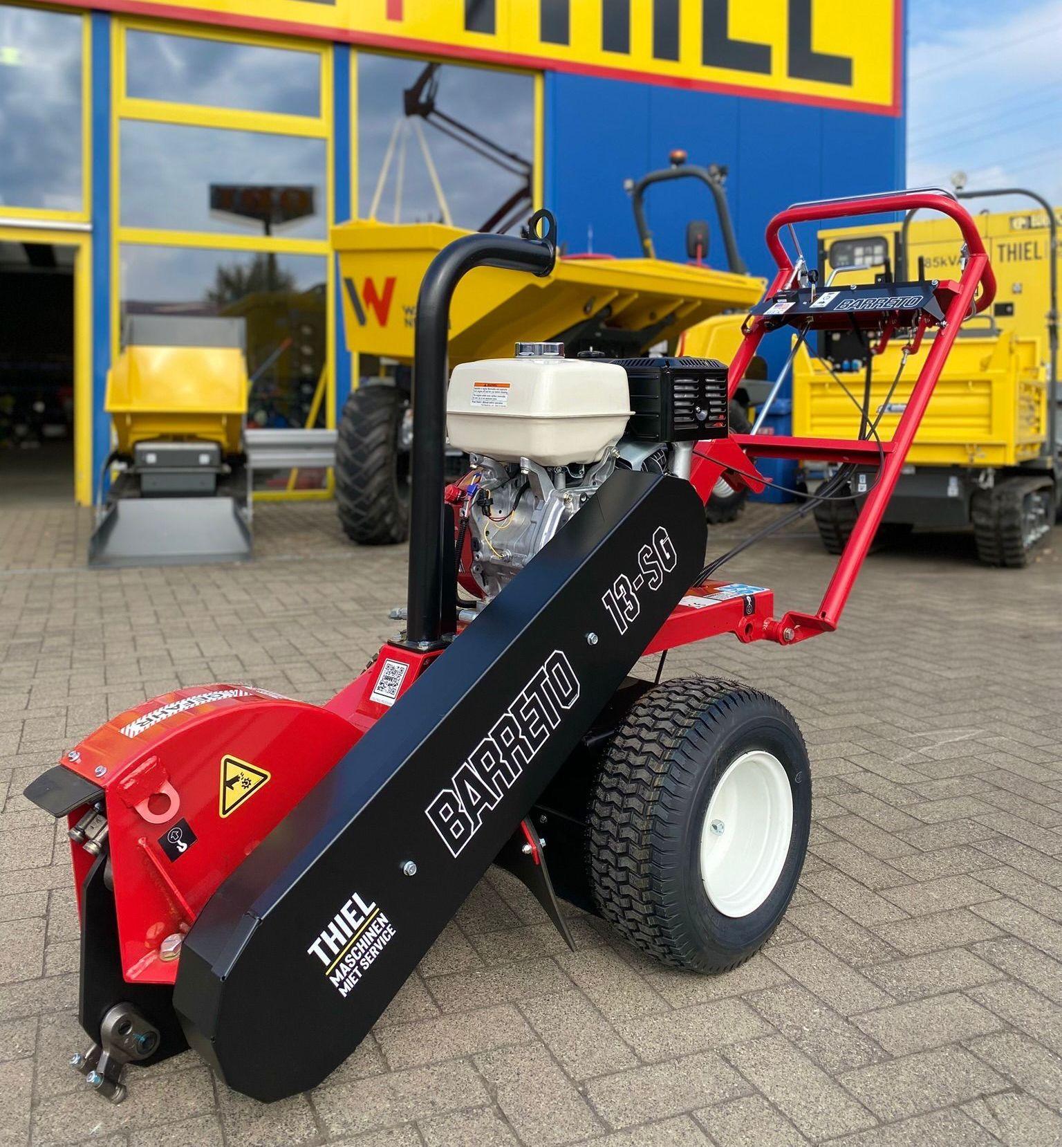 Rote Barreto 13-SG Stubbenfräse mit Benzinmotor vor Thiel Maschinenservice-Gebäude mit gelben Nutzfahrzeugen im Hintergrund.